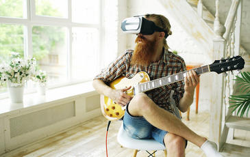 Guy playing guitar wearing VR glasses